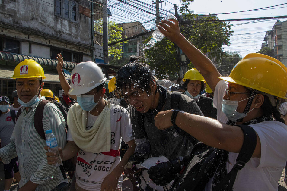 Man pours water on fellow protester to reduce the effect of teargas during the military coup demonstrations..