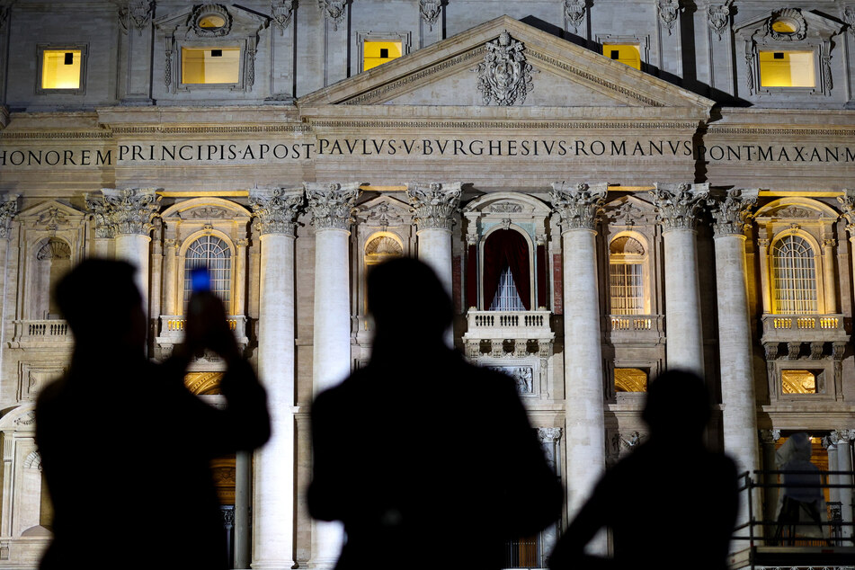 People take pictures and look at St. Peter's Basilica, ahead of the conclave, at the Vatican on May 6, 2025.