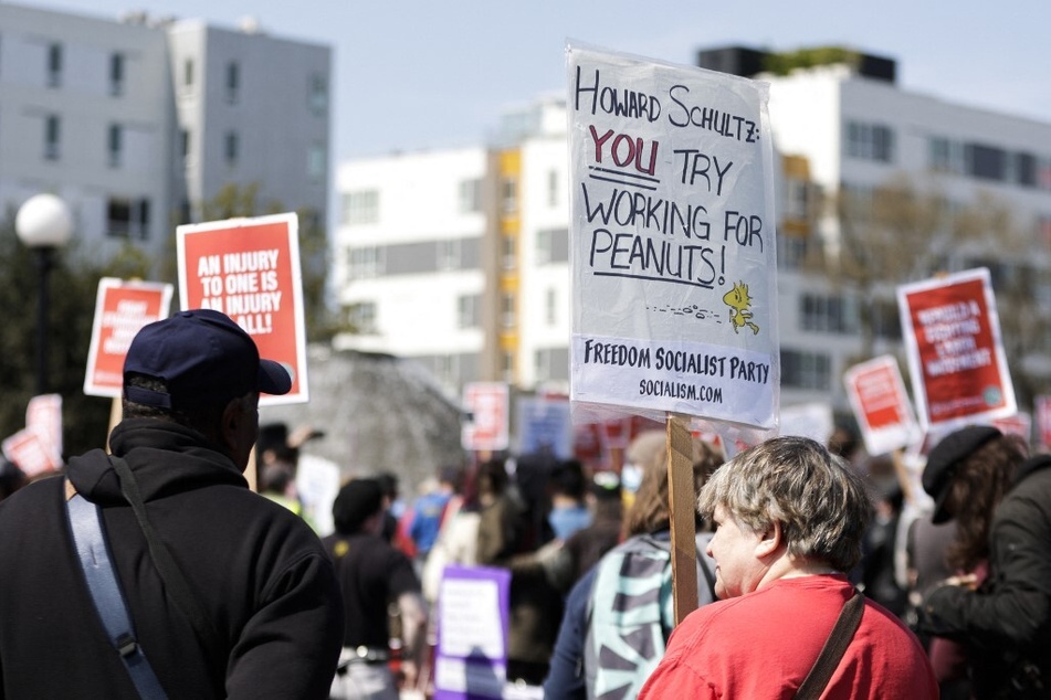 A protester holds a sign reading "Howard Schultz: you try working for peanuts" during a rally and march in Seattle, Washington.