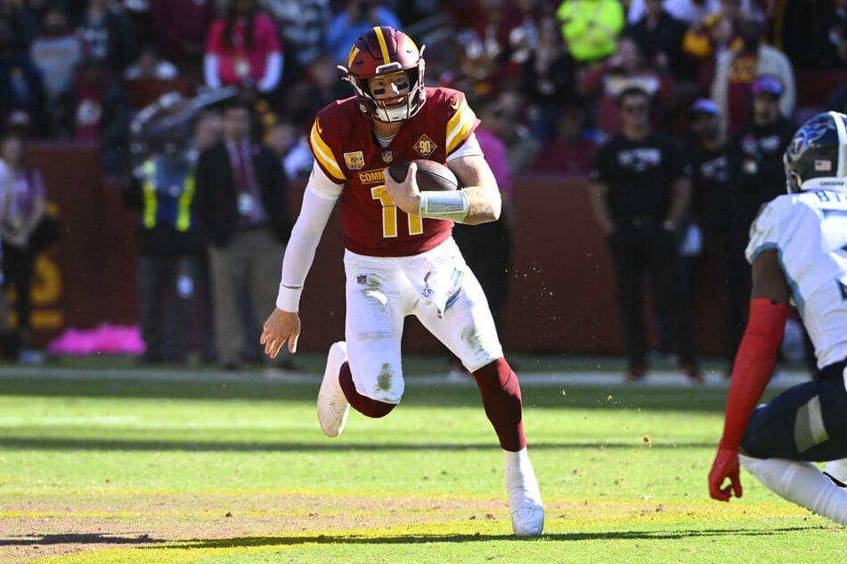 Washington Commanders quarterback Carson Wentz runs for a first down against the Tennessee Titans during the second half at FedExField.