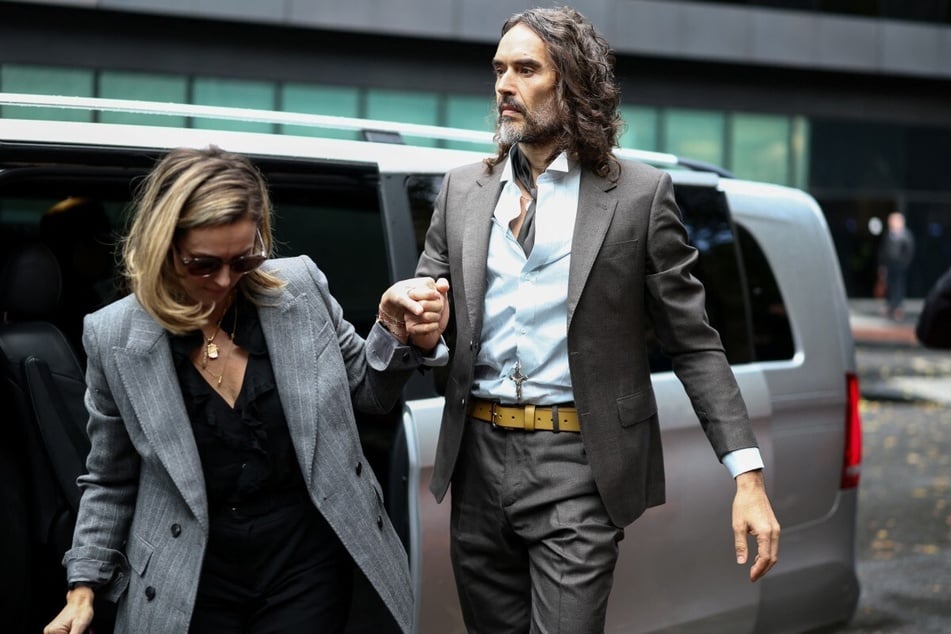 Comedian and actor Russell Brand (r.) and his wife Laura Gallacher arrive at the Southwark Crown Court in South London, UK, on October 27, 2026. Gallacher took the stand as a character witness, calling him "caring" and "a wonderful father to our children."