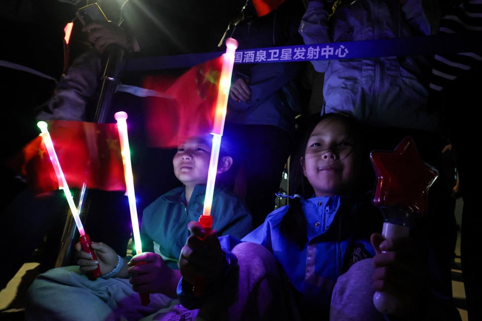 Children wave flags as people gather to watch the launch of the Long March 2F rocket carrying the Shenzhou-23 spacecraft at the Jiuquan Satellite Launch Center on May 24, 2026.