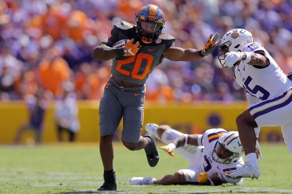 Jaylen Wright of the Tennessee Volunteers runs with the ball as Sage Ryan and Greg Brooks Jr. of the LSU Tigers defend during the second half a game at Tiger Stadium.