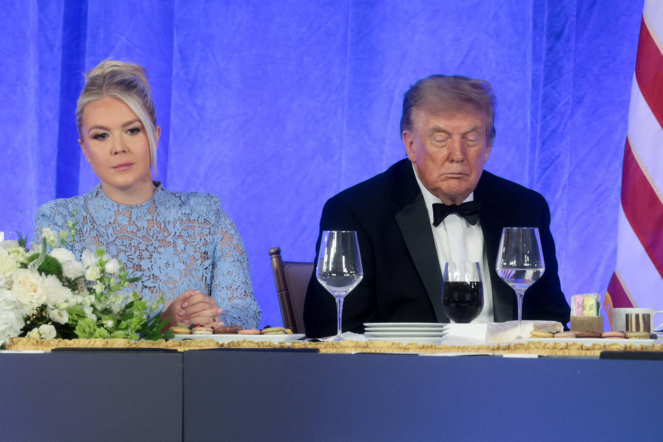 President Donald Trump (r.) and White House Press Secretary Karoline Leavitt (l.) look on as mentalist Oz Pearlman entertains attendees at the White House Correspondents' Association Dinner.