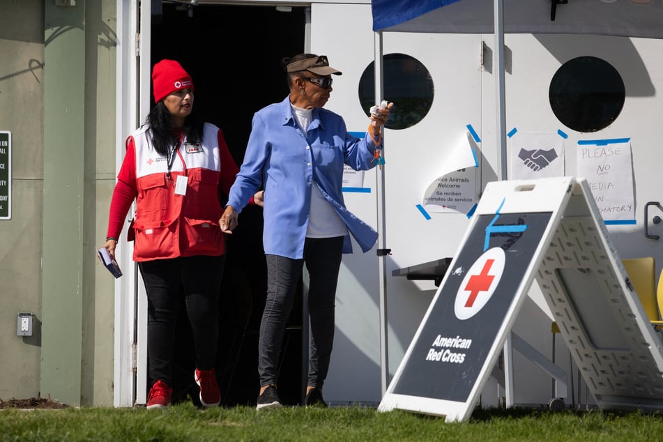 An American Red Cross member walks with an evacuee at a shelter in Fountain Valley, California, on May 24, 2026, after a chemical leak from a large storage tank threatened residents in Garden Grove.