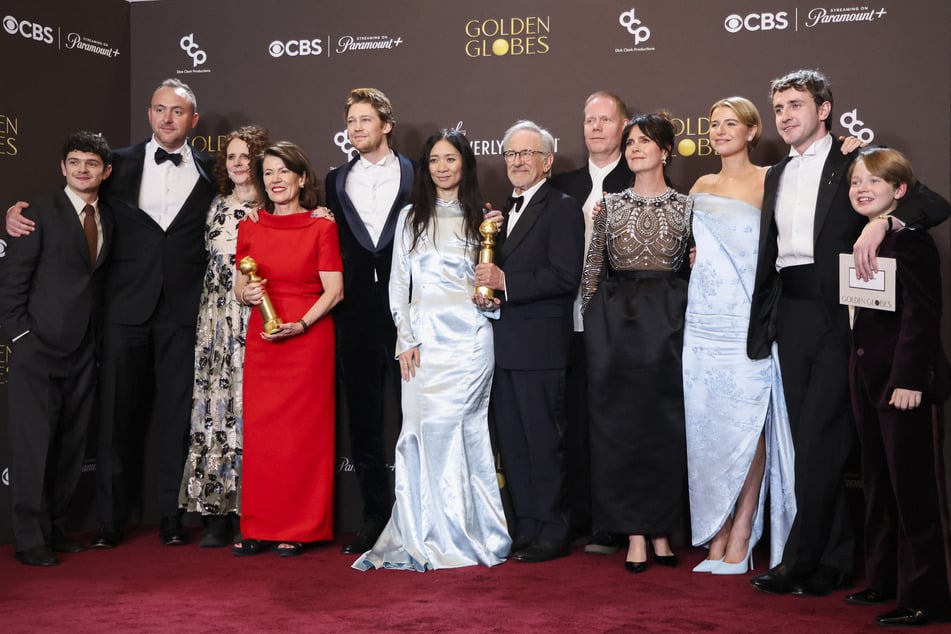 Chloe Zhao, Steven Spielberg, and cast members pose with the Best Motion Picture - Drama Award for Hamnet at the 83rd Annual Golden Globes.