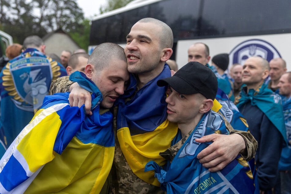 Ukrainian servicemen and former prisoners of war embrace after they set foot on Ukrainian soil after a POW swap with Russia on May 15, 2026.