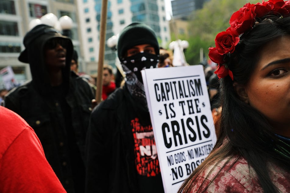 A demonstrator holds a sign reading "Capitalism Is The Crisis" during a May Day protest in New York City.
