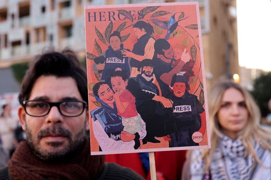 A man holds a sign honoring Palestinian journalists, many of whom have been wounded or killed in Israel's ongoing bombardment and invasion of Gaza.