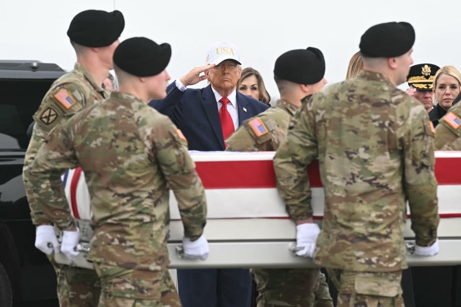 President Donald Trump salutes as members of a US Army team carry a flag-draped transfer case containing the remains of one of six US soldiers during a dignified transfer solemn event at Dover Air Force Base, in Dover, Delaware, on Saturday.