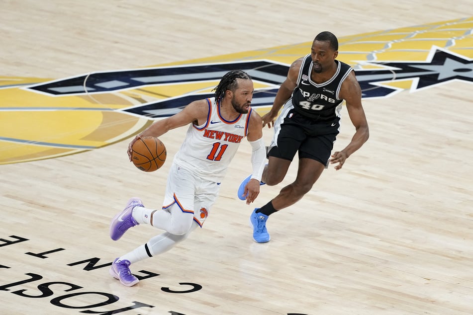 New York Knicks guard Jalen Brunson looks to move the ball past San Antonio Spurs forward Harrison Barnes during the fourth quarter of game one of the 2026 NBA Finals at Frost Bank Center.