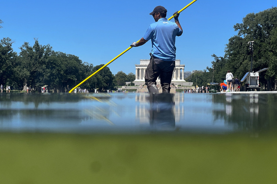 A US National Park Service employee uses a vacuum pump to clean algae off the bottom of the newly repainted Lincoln Memorial Reflecting Pool on the National Mall on June 16, 2026.