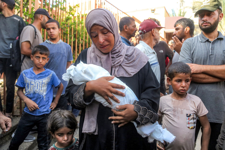 The mother of Yahya Fadi al-Najjar, an infant who died due to malnourishment, mourns as she holds his body during the funeral at Nasser Medical Complex in Khan Younis on July 20, 2025.