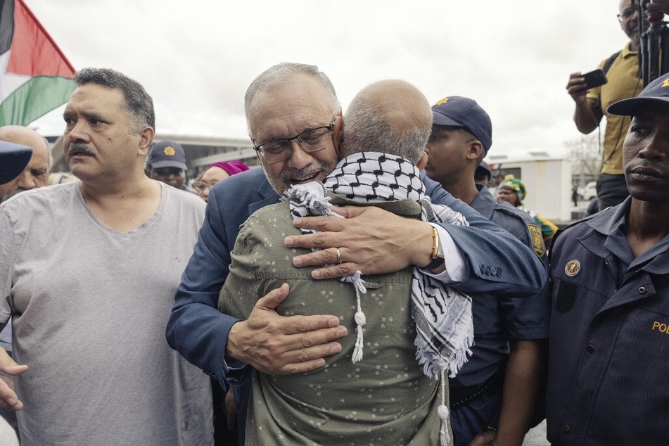Former South African Ambassador to the US Ebrahim Rasool (c.) greets relatives and supporters upon his arrival at the Cape Town International Airport.