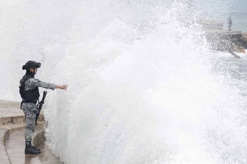 A member of Mexico's National Guard stands on the Puerto Vallarta boardwalk as waves crash against the shoreline ahead of the potential impact of Hurricane Simon in Mexico on October 11, 2026.