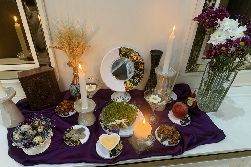 A candle burns on a Haft-Sin table to celebrate the spring holiday of Nowruz, in the home of an Iranian family in Tehran, on March 20, 2026.