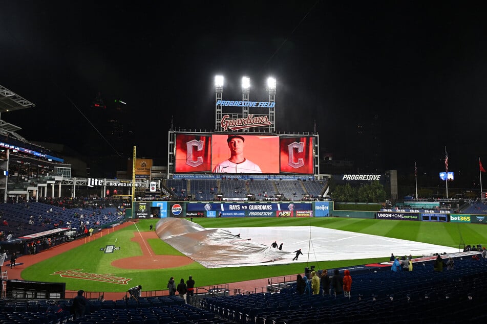 The grounds crew pulls the tarp before game four of the ALCS between the Tampa Bay Rays and the Cleveland Guardians at Progressive Field on October 16, 2026. The game was ultimately postponed until Saturday due to weather.