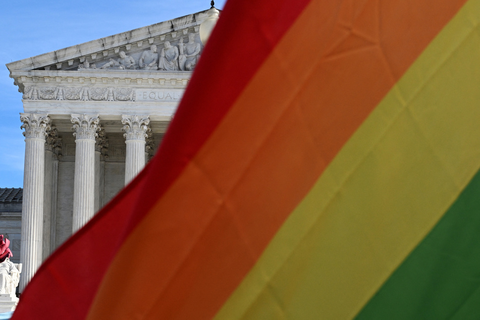 People raise flags during a rally in support of LGBTQ+ rights outside the Supreme Court in Washington DC.