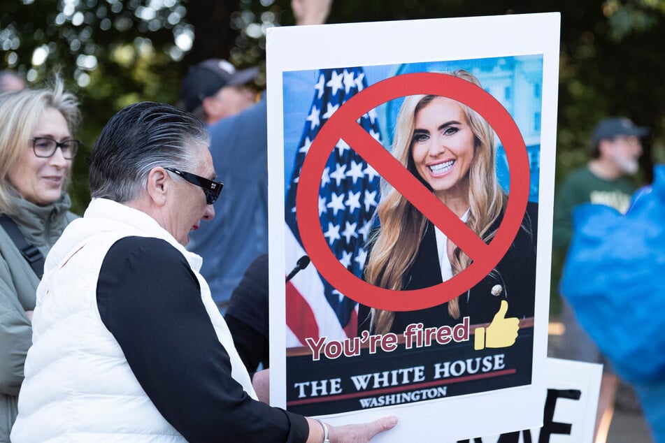 A demonstrator holds a sign featuring former White House Press Secretary Katie Zacharia during a "No Kings" protest at Falls Park on the Reedy on Saturday. Zacharia was ousted from her role after less than a week on the job.