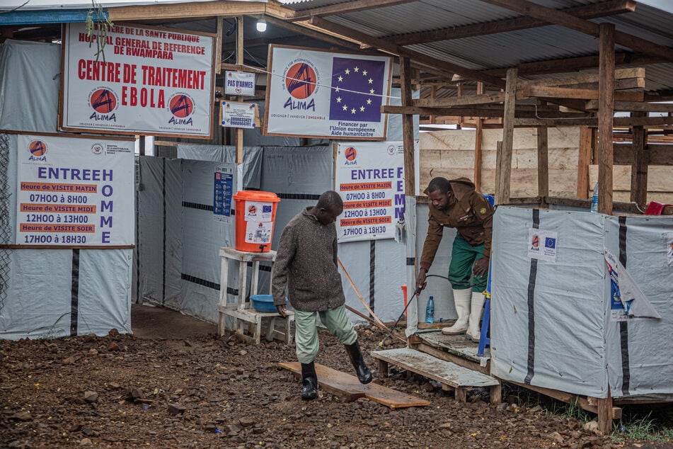 A hygiene worker disinfects a person's feet at the entrance to the Rwampara Ebola Treatment Center in Bunia, Ituri, Democratic Republic of Congo, on July 13, 2026.