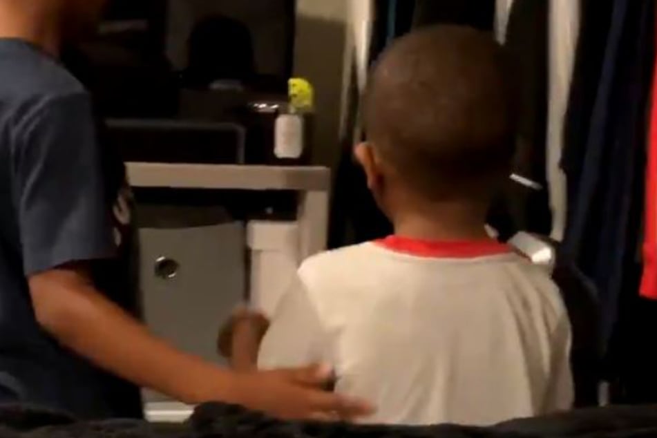 The big brother puts his arm around his now-calm little sibling.