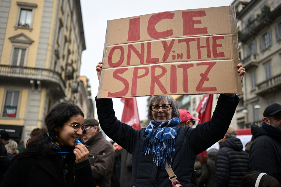 A demonstrator holds a placard reading "Ice only in the spritz" during a protest against US Immigration and Customs Enforcement (ICE) ahead of the Milano Cortina 2026 Olympic Games in Milan, northern Italy, on January 31, 2026.