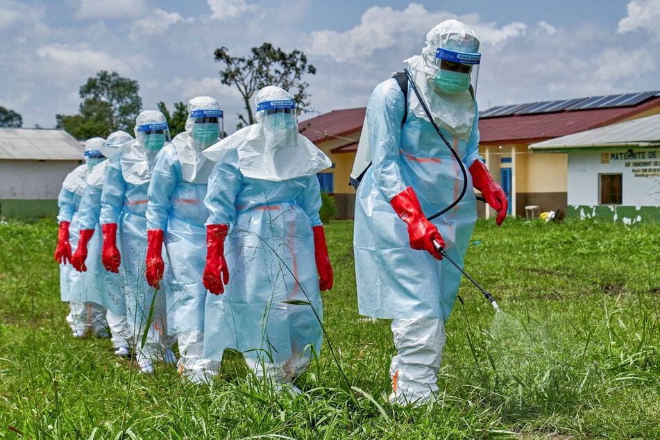 Red Cross workers walk in a formation as they disinfect Rwampara general hospital before handling the body of a person who died of Ebola in Rwampara outside Bunia, Ituri province, Democratic Republic of Congo.