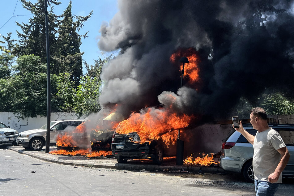 A man takes pictures of burning vehicles following an Israeli airstrike that hit a car in Sidon, Lebanon, on June 10, 2026.