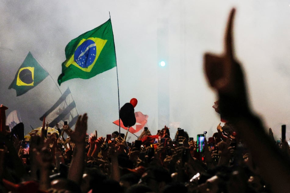 Brazilian flags flutter in the wind as supporters gather to watch President Luiz Inacio Lula da Silva's victory speech in Sao Paulo.