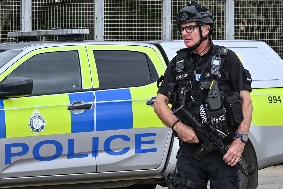 An armed policeman guards a roadblock at an entrance to RAF Fairford base in Fairford, south-west England on September 27, 2026, as UK counter-terrorism police investigate an incident. President Donald Trump claims the accused attackers aimed to do "big damage."