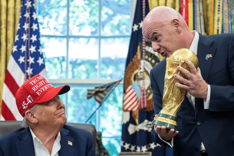 FIFA President Gianni Infantino (r.) hands the World Cup trophy to US President Donald Trump in the Oval Office of the White House on August 22, 2025.