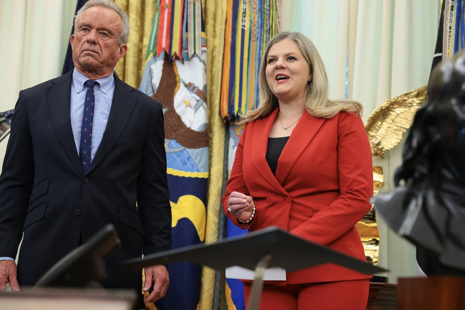 Deputy Assistant to the President for Domestic Policy Dr. Heidi Overton (r.), next to Health and Human Services Secretary Robert F. Kennedy Jr. (l.), speaks in the Oval Office before Donald Trump signs an executive order calling for childhood vaccine shots to be spaced out into separate visits on August 10, 2026.