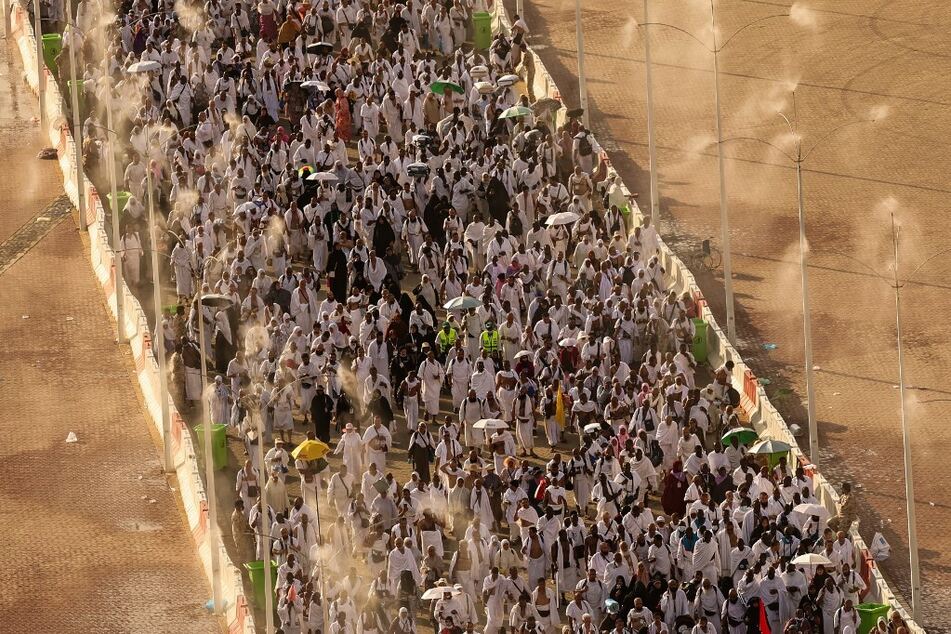 Muslim pilgrims walk under mist dispensers as they arrive to perform the symbolic "stoning of the devil" ritual during the annual hajj pilgrimage in Mina on June 16, 2024.