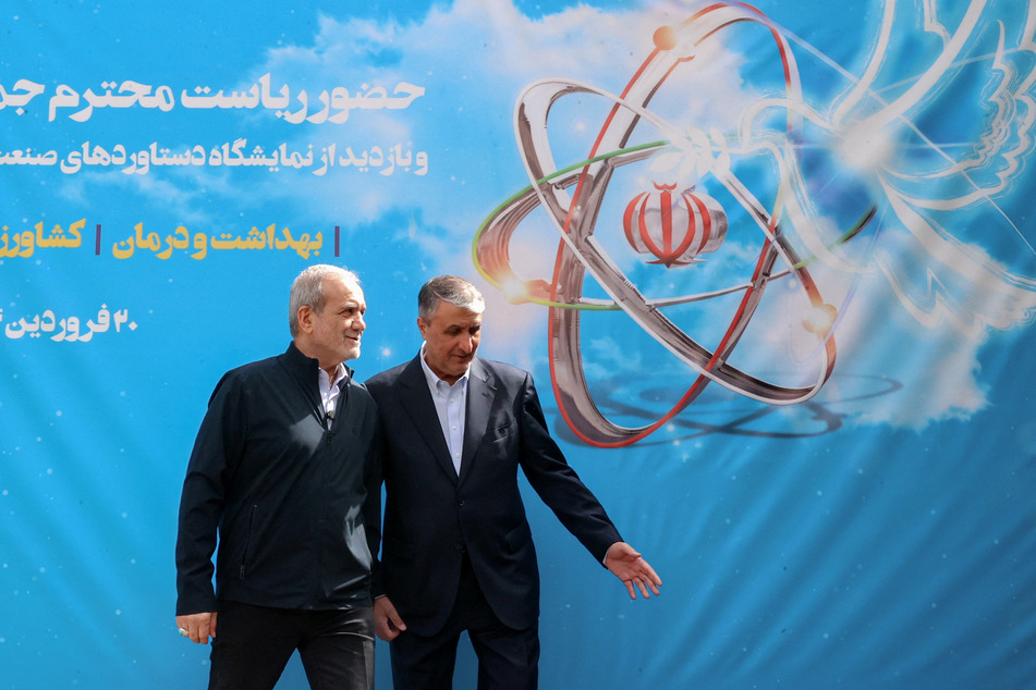 A handout picture provided by the Iranian presidency shows President Masoud Pezeshkian (L) and the Atomic Energy Organization of Iran (AEOI) chief Mohammad Eslami (R) during the "National Day of Nuclear Technology" in Tehran, on April 9, 2025.
