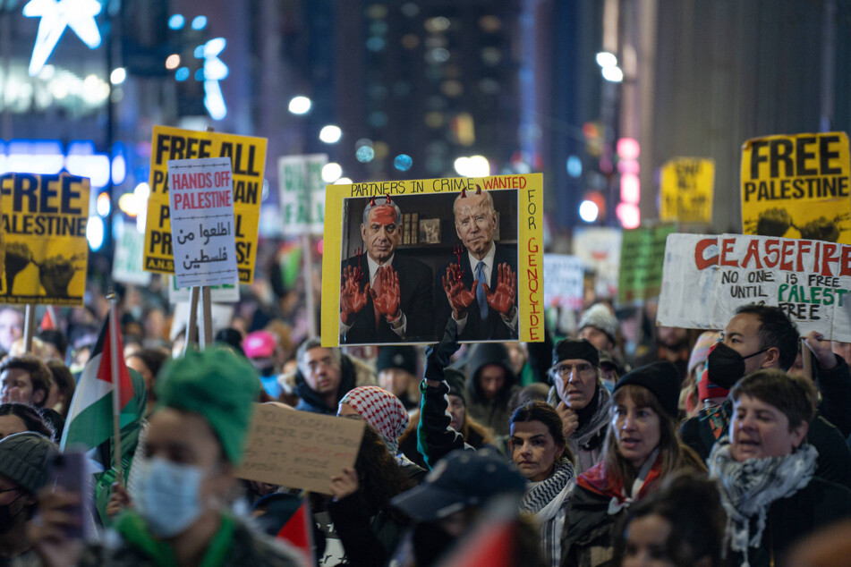 New Yorkers calling for a permanent ceasefire and Palestinian freedom raise a sign with Israeli Prime Minister Benjamin Netanyahu and US President Joe Biden with red hands and red horns, reading "Partners In Crime, Wanted for Genocide."
