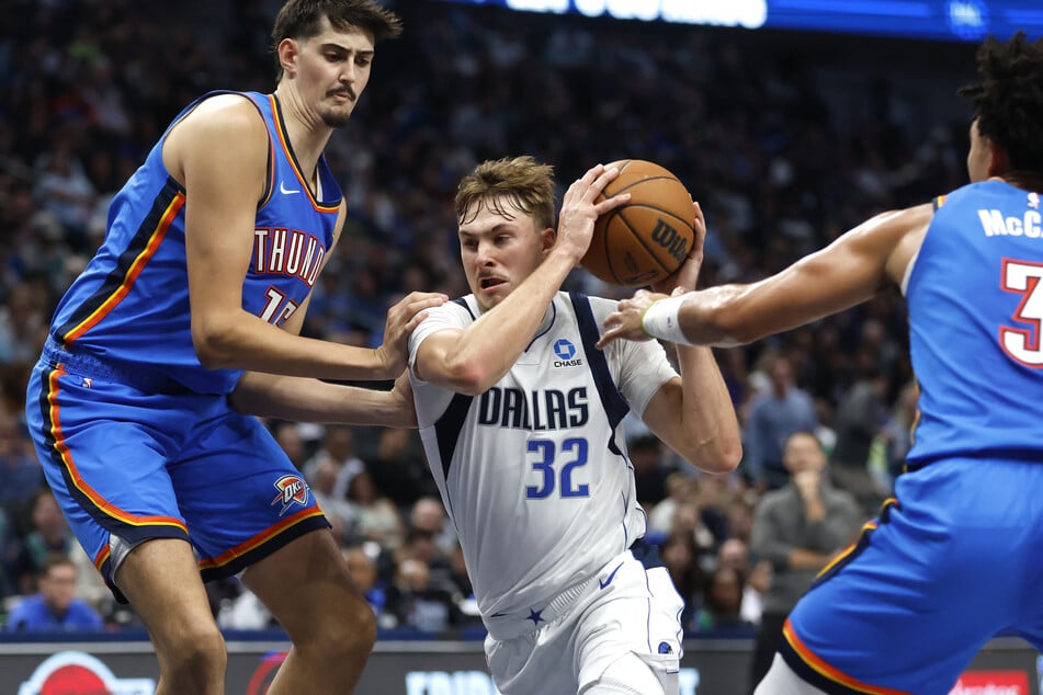 Cooper Flagg (c.) of the Dallas Mavericks goes to the basket as Aday Mara (l.) and Jared McCain (r.) of the Oklahoma City Thunder defend during the first half at American Airlines Center on October 28, 2026.