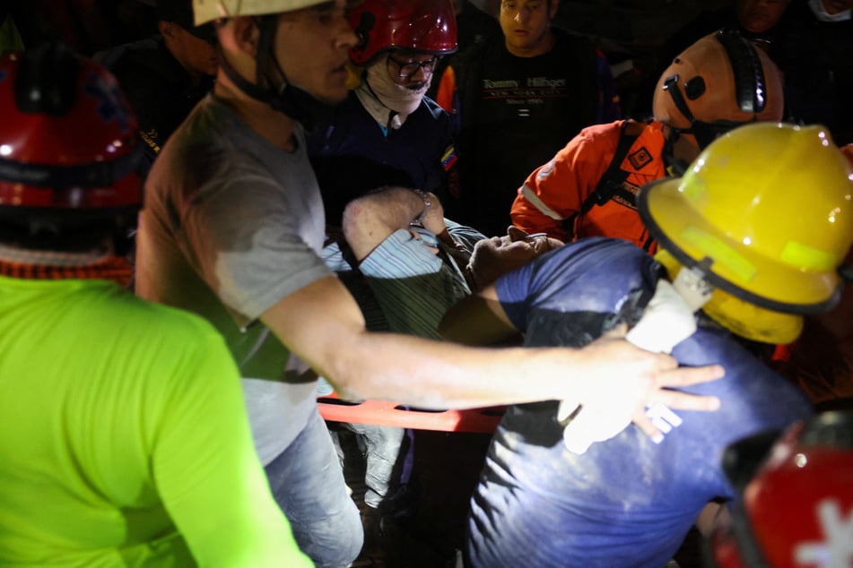 Rescuers move a casualty on a stretcher as emergency services work at the site of a collapsed building in Caracas, Venezuela, on June 25, 2026.
