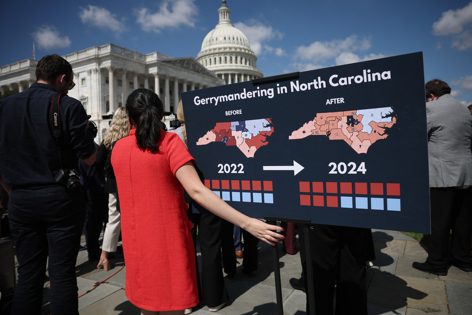 A staff member holds a chart showing the redistricting that has taken place in North Carolina as members of Congress speak during a press conference outside the US Capitol on September 18, 2025.