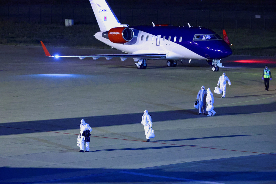 Personnel in hazmat suits walk near a plane carrying passengers evacuated from the cruise ship MV Hondius after it landed at the Eindhoven Air Base in the Netherlands on May 12, 2026.