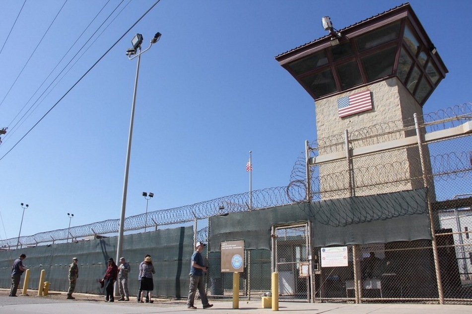 Poeple walk past a guard tower outside the fencing of Camp 5 at the US Military's Prison in Guantanamo Bay, Cuba.