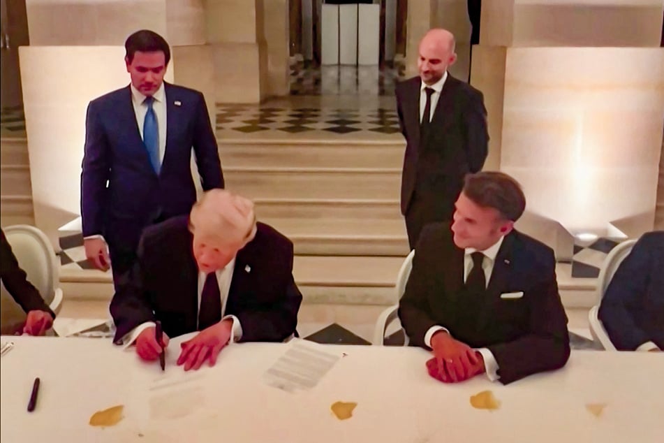 President Donald Trump (l.), alongside France's President Emmanuel Macron, signs a deal with Iran to end the Middle East war, inside Chateau de Versailles on June 17, 2026.