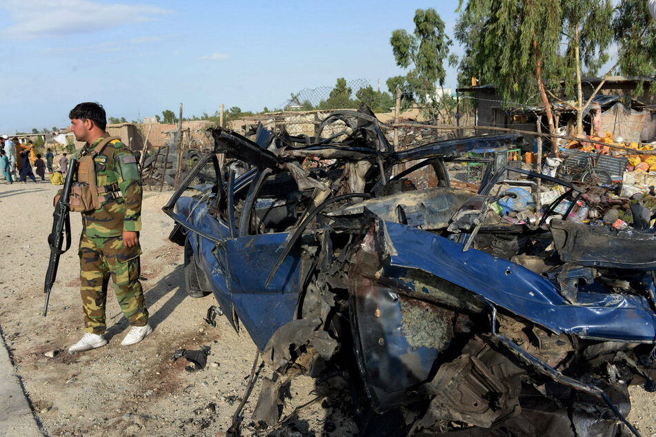 An Afghan soldier stands guard at the site of a bomb explosion in the Khogiani district of Nangarhar province.