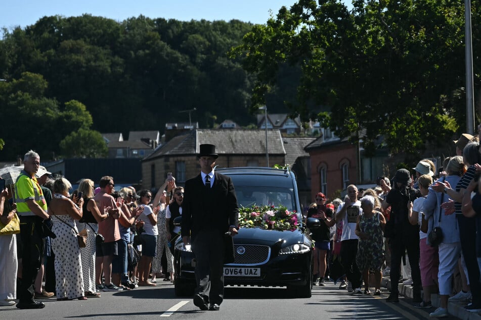 Mourners and fans line the streets to pay their respects as a hearse carrying the coffin of the late singer Bonnie Tyler is driven through her hometown of Mumbles, southwest Wales, on August 15, 2026.