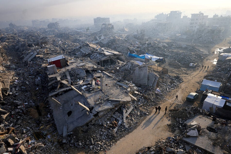 Palestinians walk past the rubble of buildings destroyed by Israel in Gaza City.