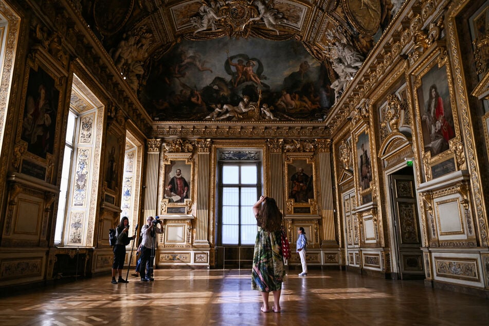 Visitors at the Louvre museum in Paris, France, are seen taking photos during the reopening to the public of the Apollo Gallery, where French crown jewels were stolen in 2025. Two men were arrested for taping paintings on the same wall that hosts the Mona Lisa on September 19, 2026, according to authorities.