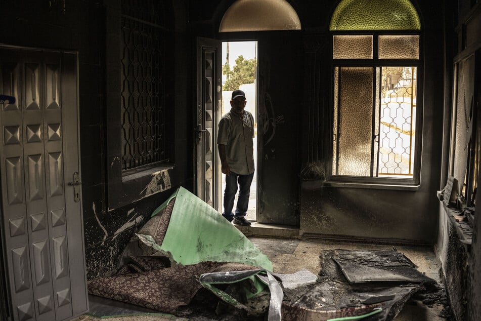 A Palestinian man assesses the damage at a mosque following an arson attack by Israeli settlers in Mikhmas, in the Israeli-occupied West Bank, on October 14, 2026.