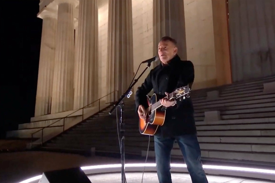 Bruce Springsteen sings and strums his guitar alone in front of the Lincoln Memorial.