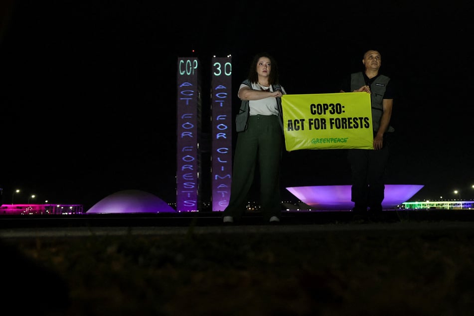 Greenpeace activists hold a sign reading "COP30: Act for Forests" outside Brazil's National Congress in Brasilia on October 11, 2025.