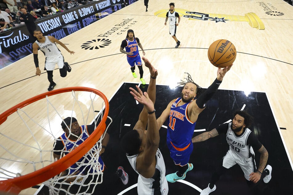 New York Knicks guard Jalen Brunson drives to the basket past San Antonio Spurs forward Julian Champagnie during game five of the 2026 NBA Finals at Frost Bank Center.