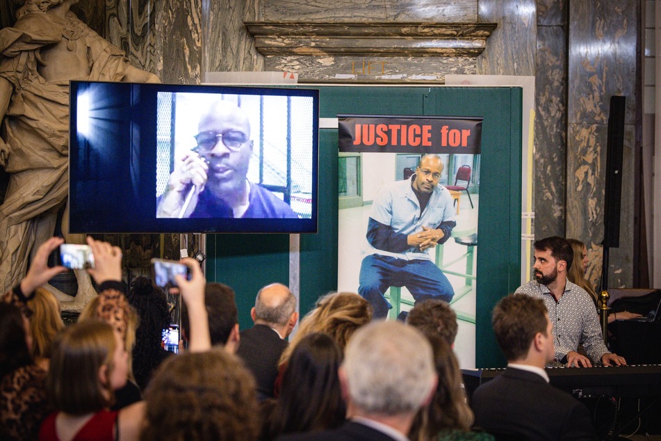 Spanish jazz pianist Albert Marques (r.) looks towards a video of Keith LaMar performing via an amplified telephone from the Ohio State Penitentiary, where he is sentenced to death.